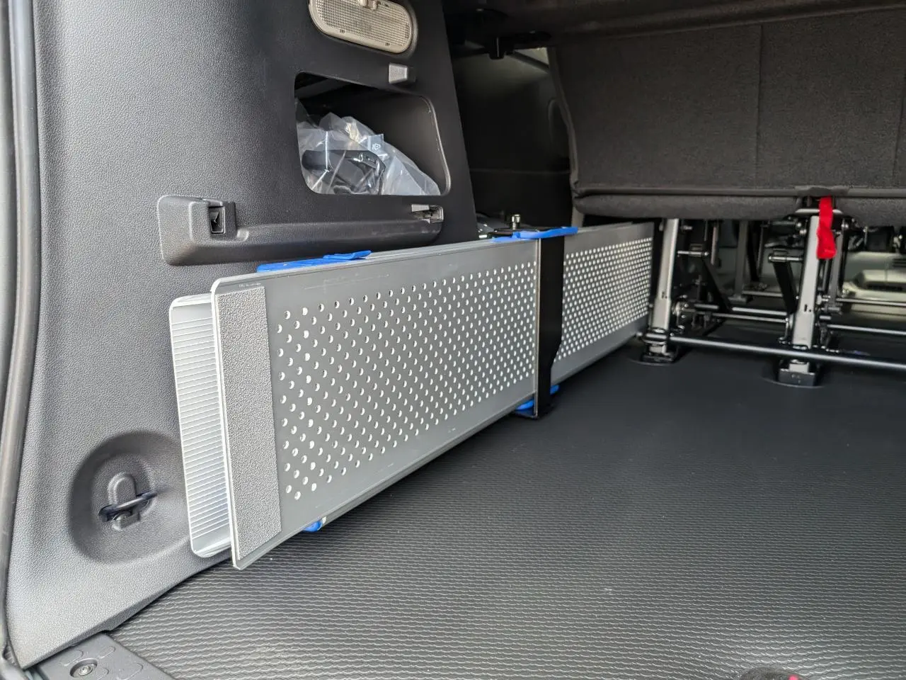 Vue intérieure du coffre arrière du Renault Trafic Fourgon gris, montrant une rampe amovible en aluminium ajouré côté gauche.