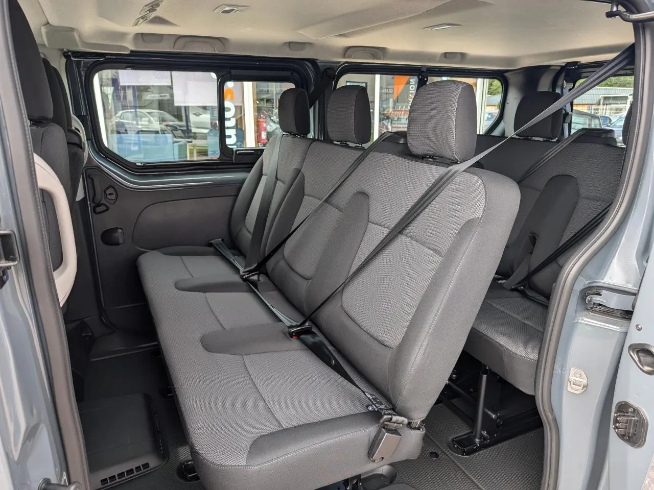 Vue intérieure côté droit sur les sièges gris tissu Kompo Black du Renault Trafic Fourgon L2 2025 avec ceintures attachées.