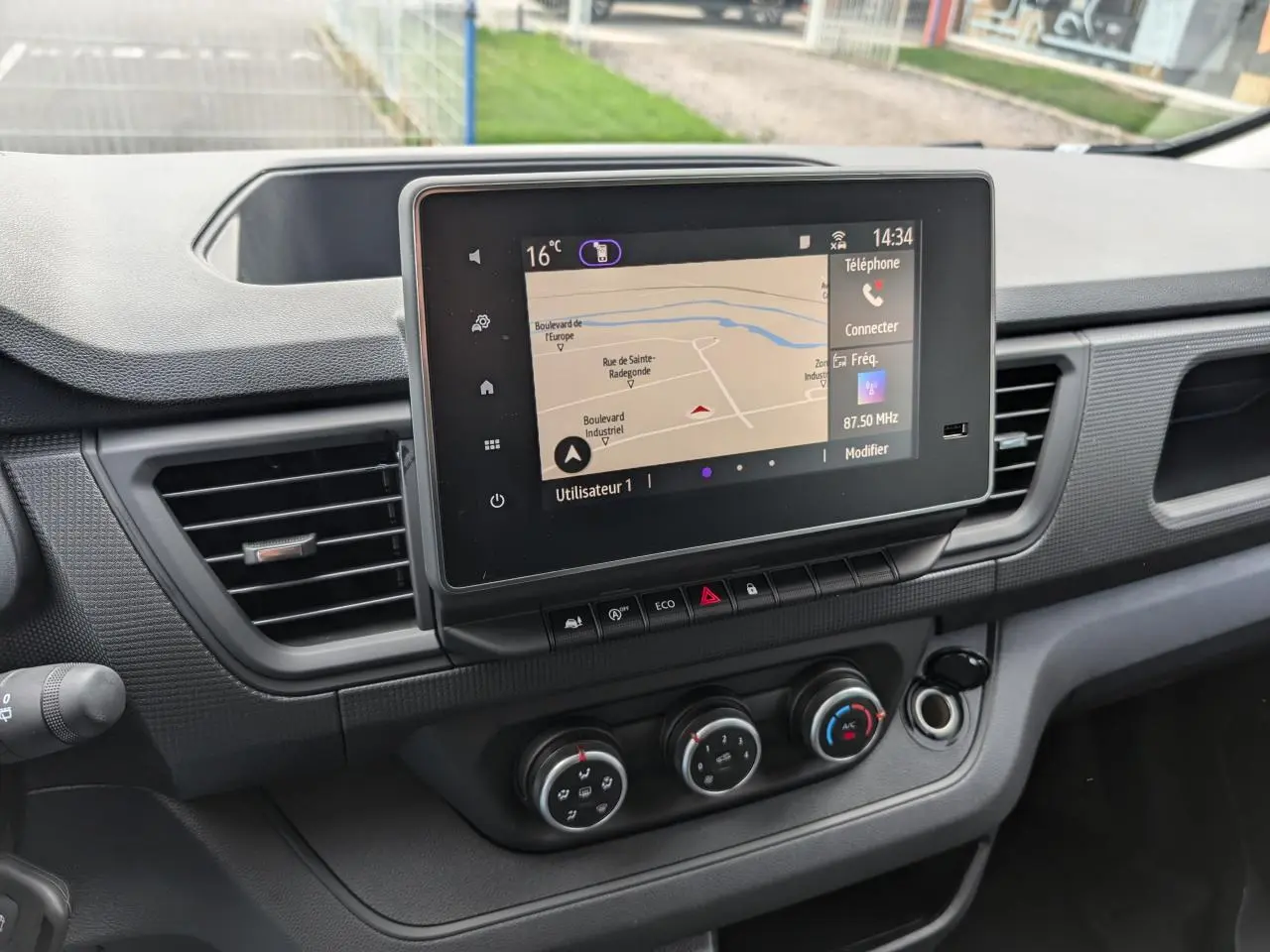 Vue rapprochée du tableau de bord du Renault Trafic Fourgon 2025, mettant en valeur l'écran tactile central et les commandes de climatisation.