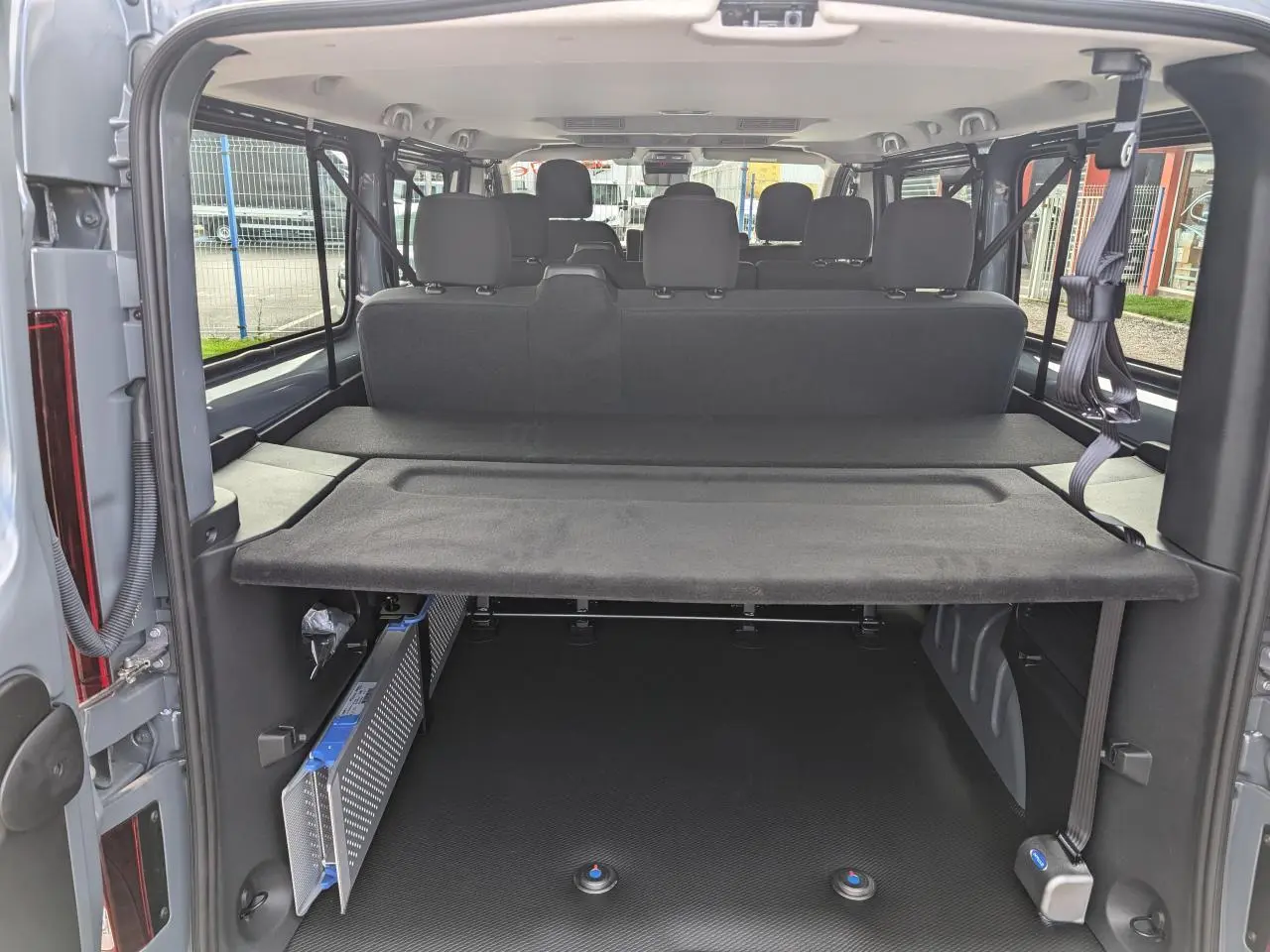 Vue arrière ouverte du Renault Trafic Fourgon gris 2025, montrant l'espace de chargement avec banquettes et ceintures de sécurité.