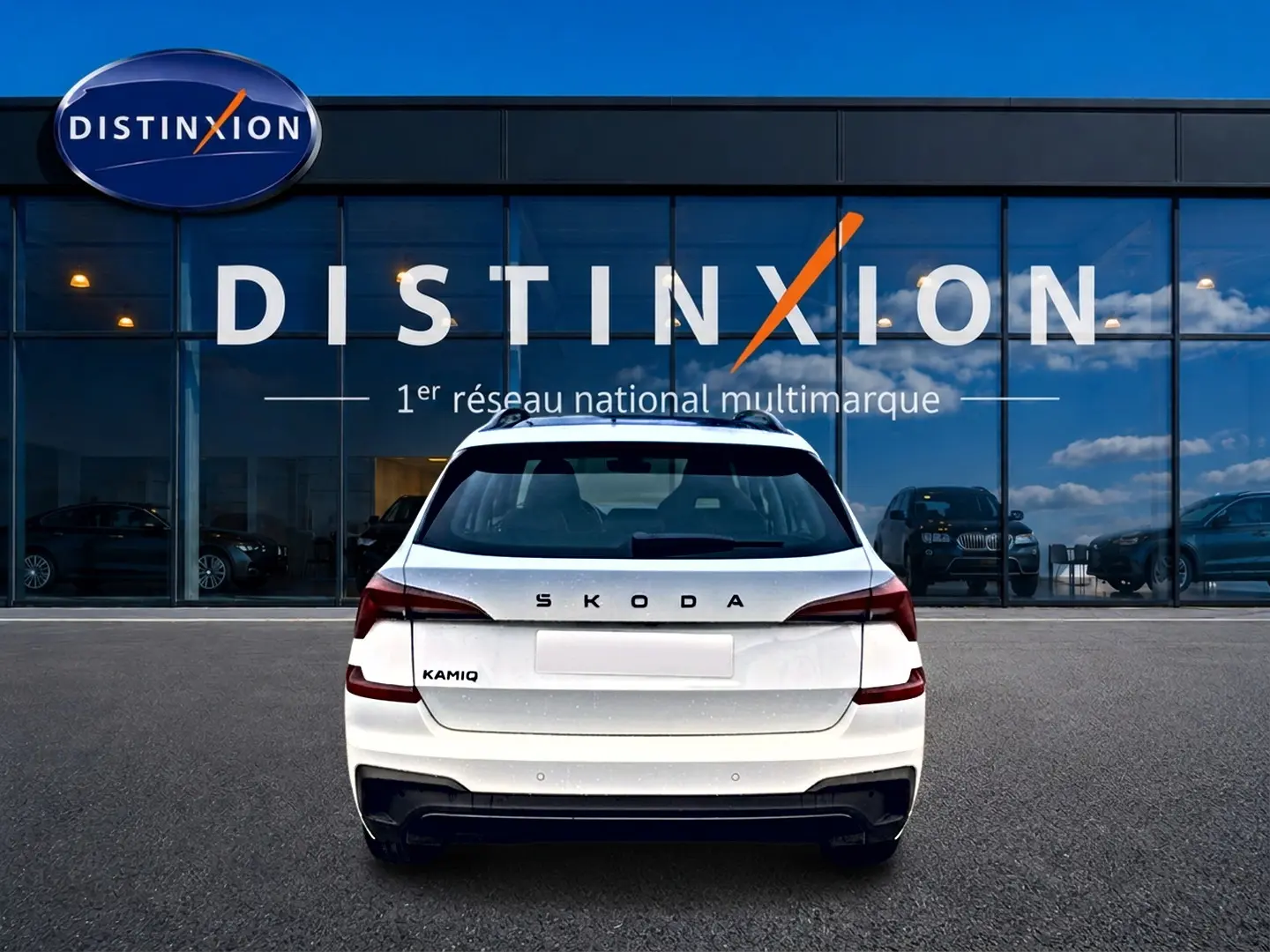 Vue arrière d'un Skoda Kamiq blanc nacré garé devant une vitrine avec logo Distinxion.