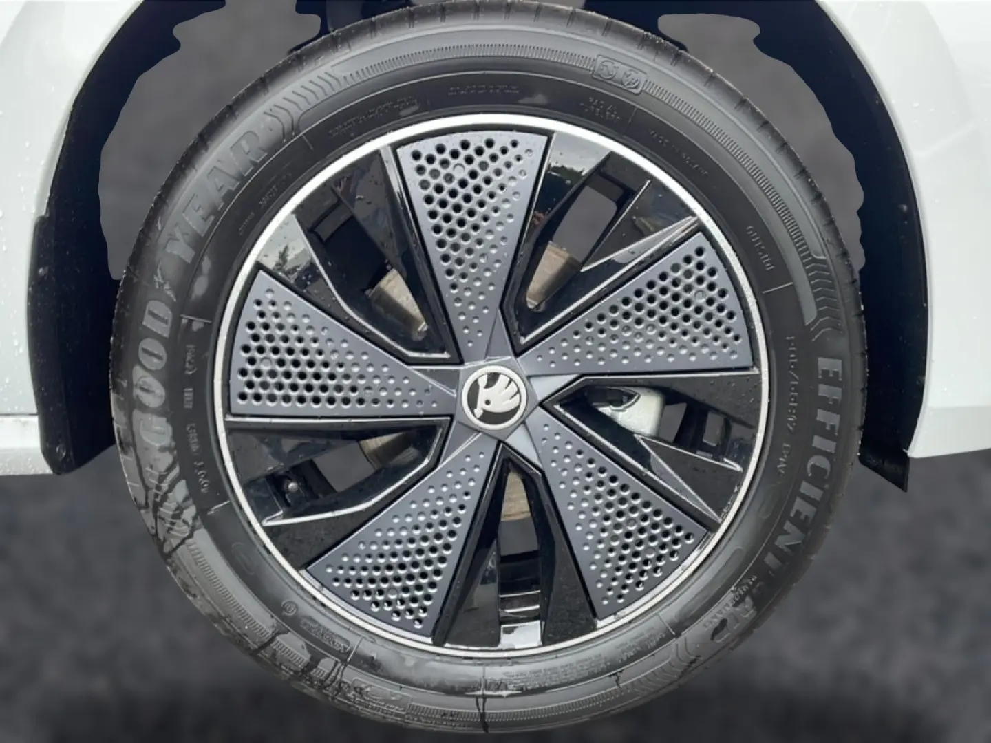Gros plan sur la jante alu noire et grise du Skoda Kamiq blanc nacré, mettant en valeur le logo central et le pneu Goodyear.