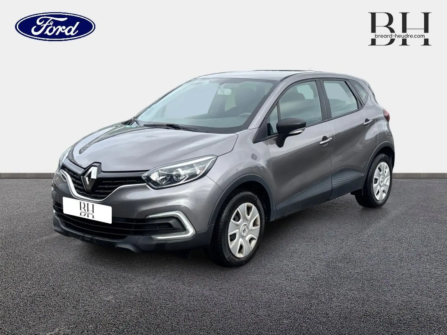 Renault Captur Gris Cassiopée en 3/4 avant droit, avec jantes acier et détails noirs sur les rétroviseurs.