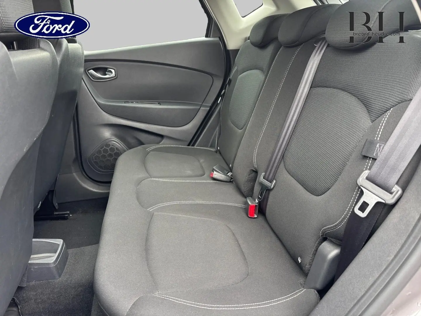 Vue intérieure côté gauche sur la banquette arrière noire avec ceintures de sécurité et porte arrière d'une Renault Captur.