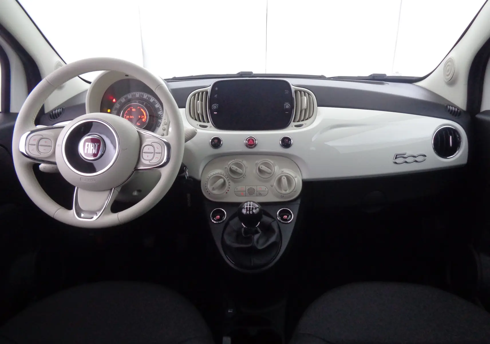 Vue frontale de l'habitacle blanc gelato de la Fiat 500 1.0 Hybrid 2023 avec tableau de bord épuré et volant multifonction.