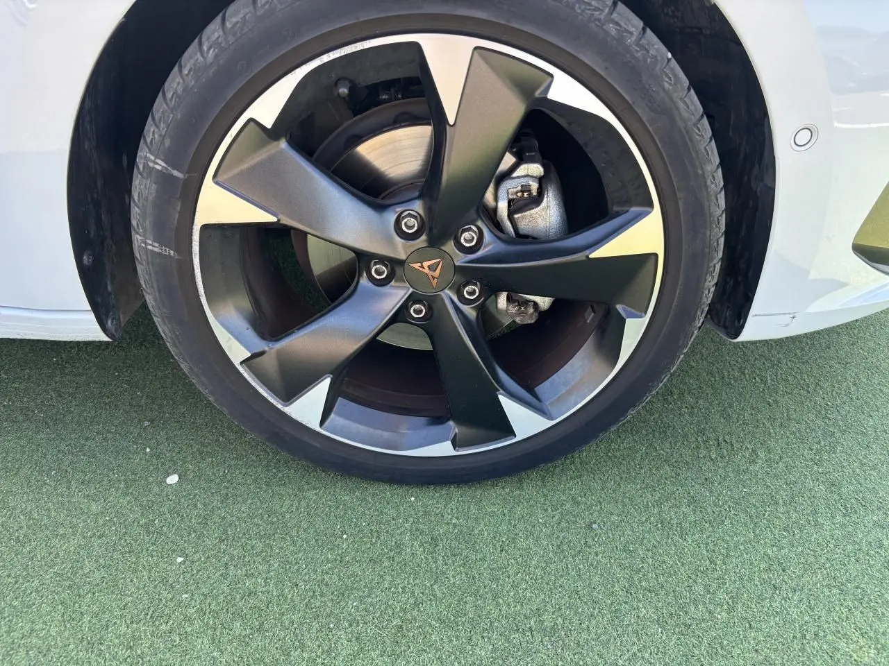 Gros plan sur la jante alliage 18 pouces noire et argentée du côté avant droit d'une CUPRA Leon Sportstourer blanc Nevada.