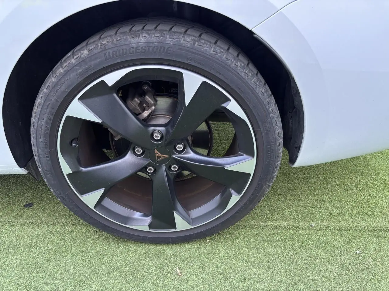 Gros plan sur la jante alliage 18 pouces noire et argentée du côté arrière droit d'une CUPRA Leon Sportstourer blanc Nevada.