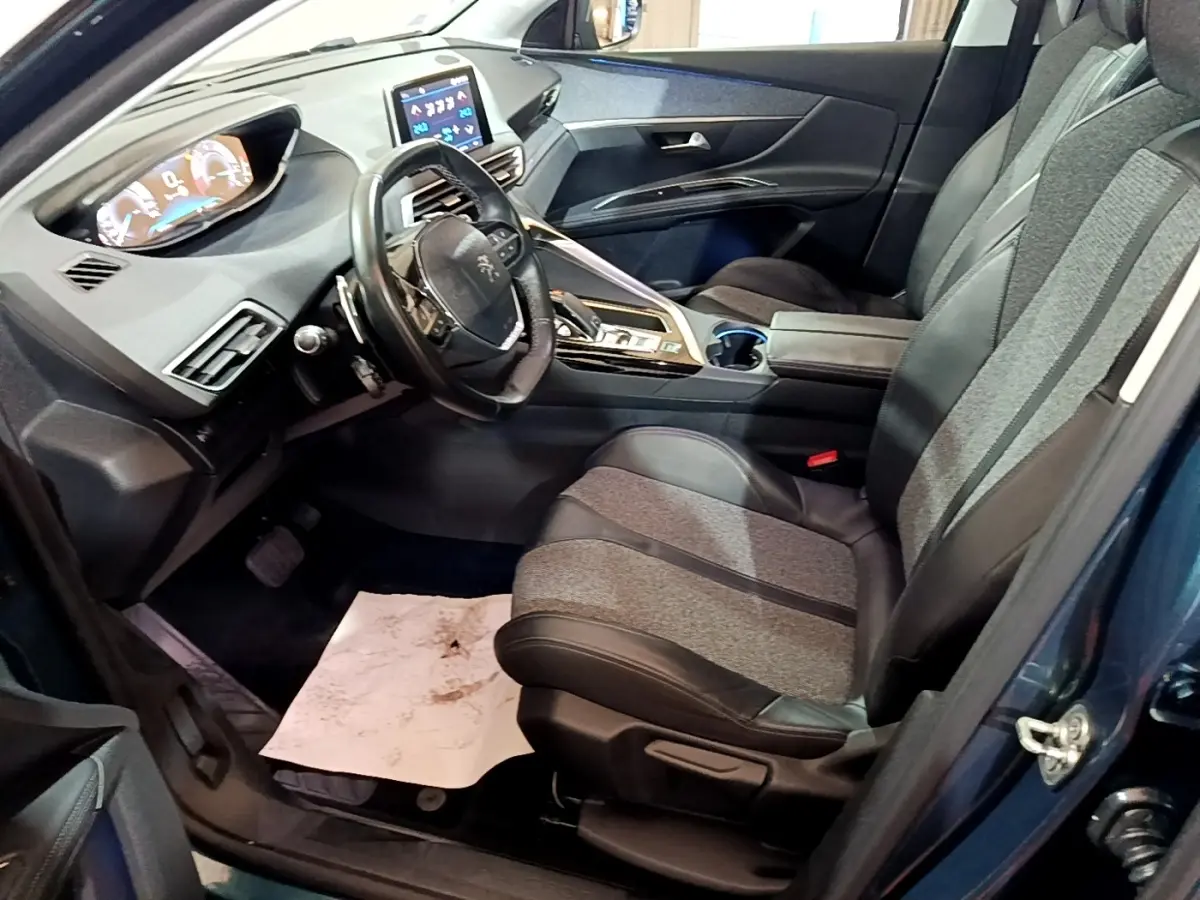 Vue intérieure côté conducteur du Peugeot 5008 bleu 2018, avec tableau de bord digital et sièges en tissu et cuir noir.