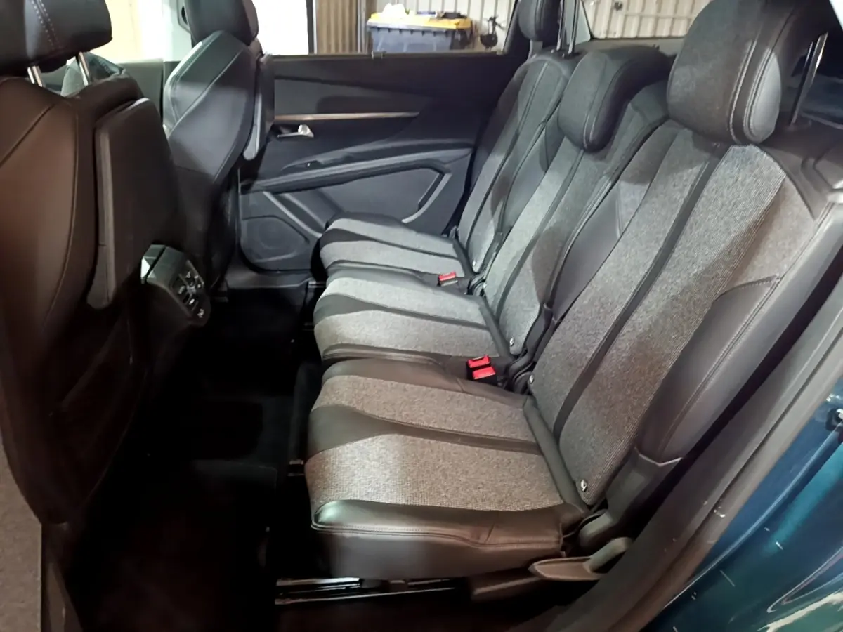 Vue latérale droite sur la banquette arrière grise et noire du Peugeot 5008 bleu, avec ceinture rouge visible.