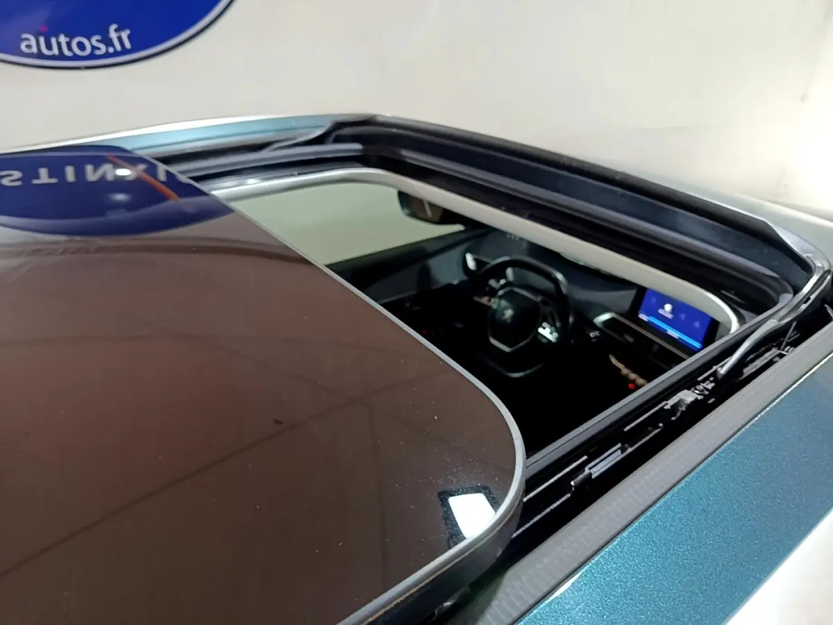 Vue plongeante sur l'intérieur d'un Peugeot 5008 bleu 2018 via son toit ouvrant panoramique ouvert.