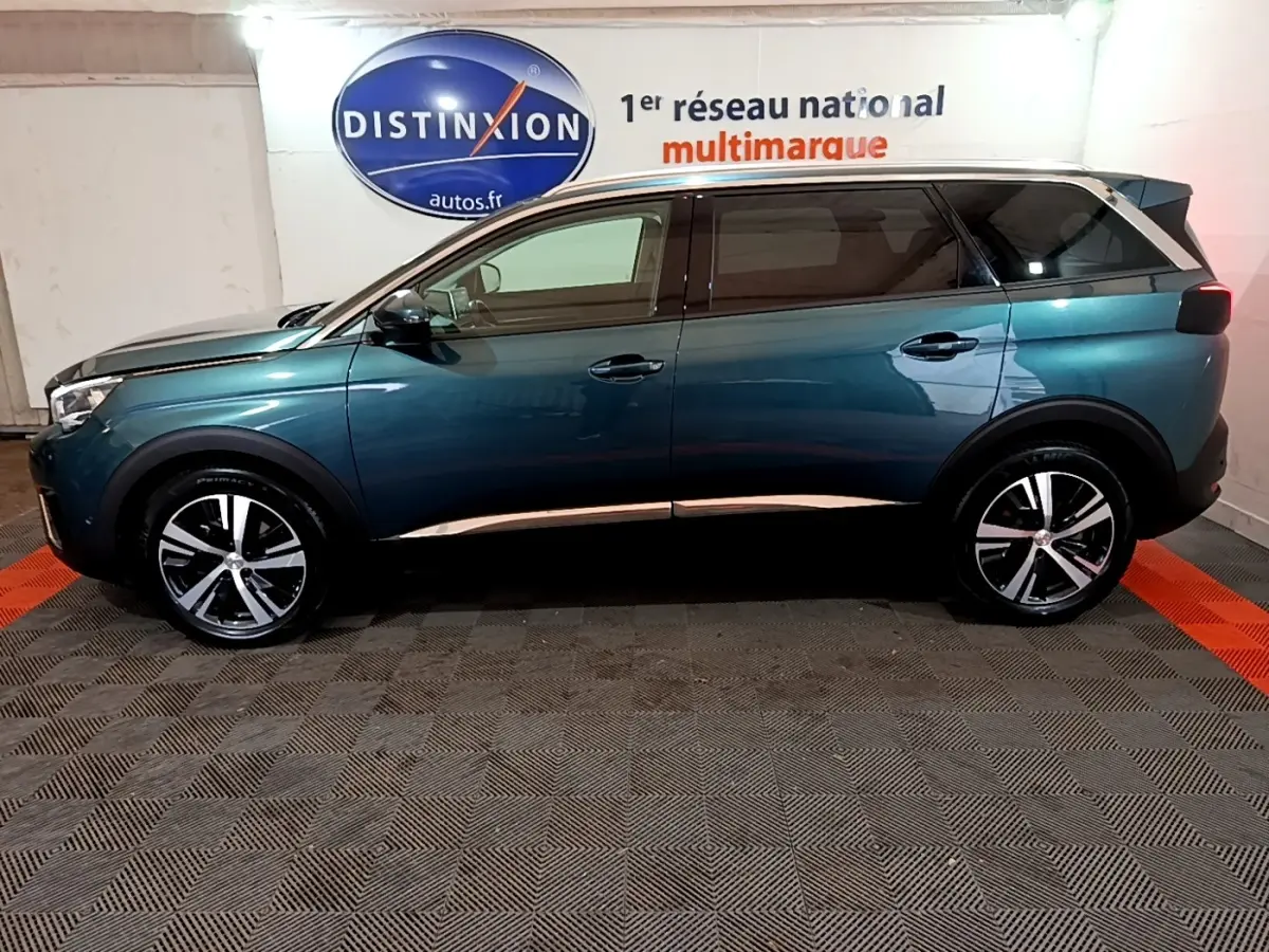 Profil droit du Peugeot 5008 bleu 2018, SUV avec jantes alliage et toit noir contrasté dans un showroom.