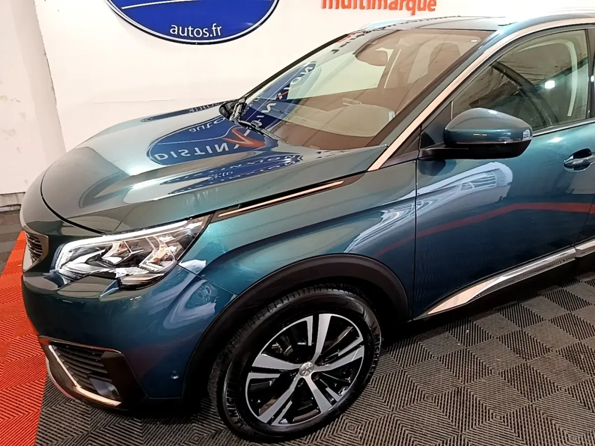 Vue 3/4 avant droit d'un Peugeot 5008 bleu métallisé avec jantes alliage et rétroviseurs noirs brillants.