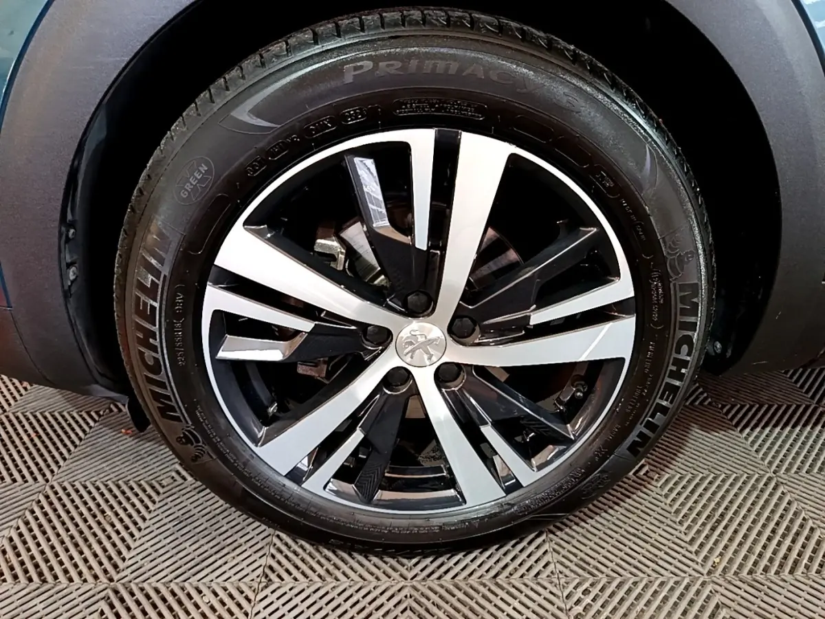 Gros plan sur la jante alliage bicolore du Peugeot 5008 bleu, mettant en valeur le logo lion central.