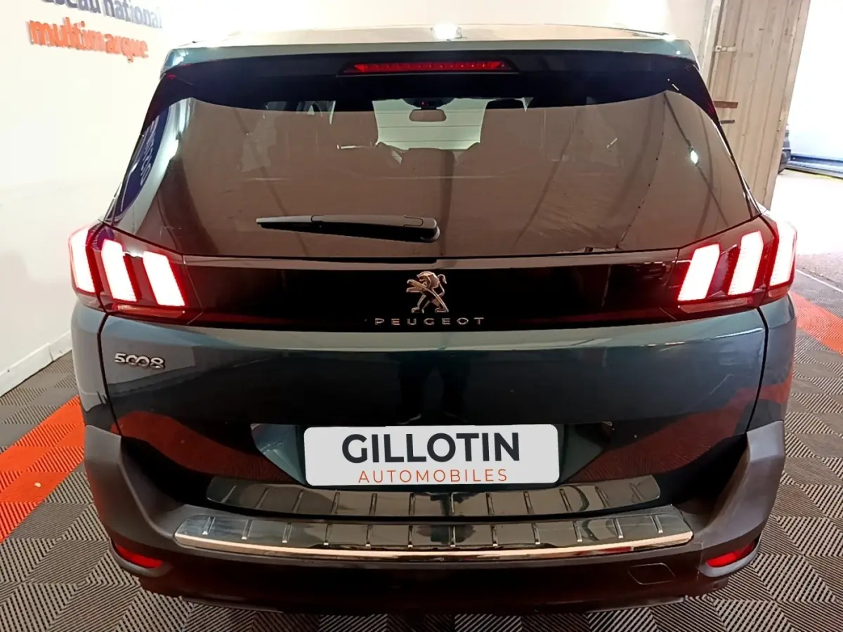 Vue arrière d'un Peugeot 5008 bleu avec feux arrière LED caractéristiques et logo lion central visible.