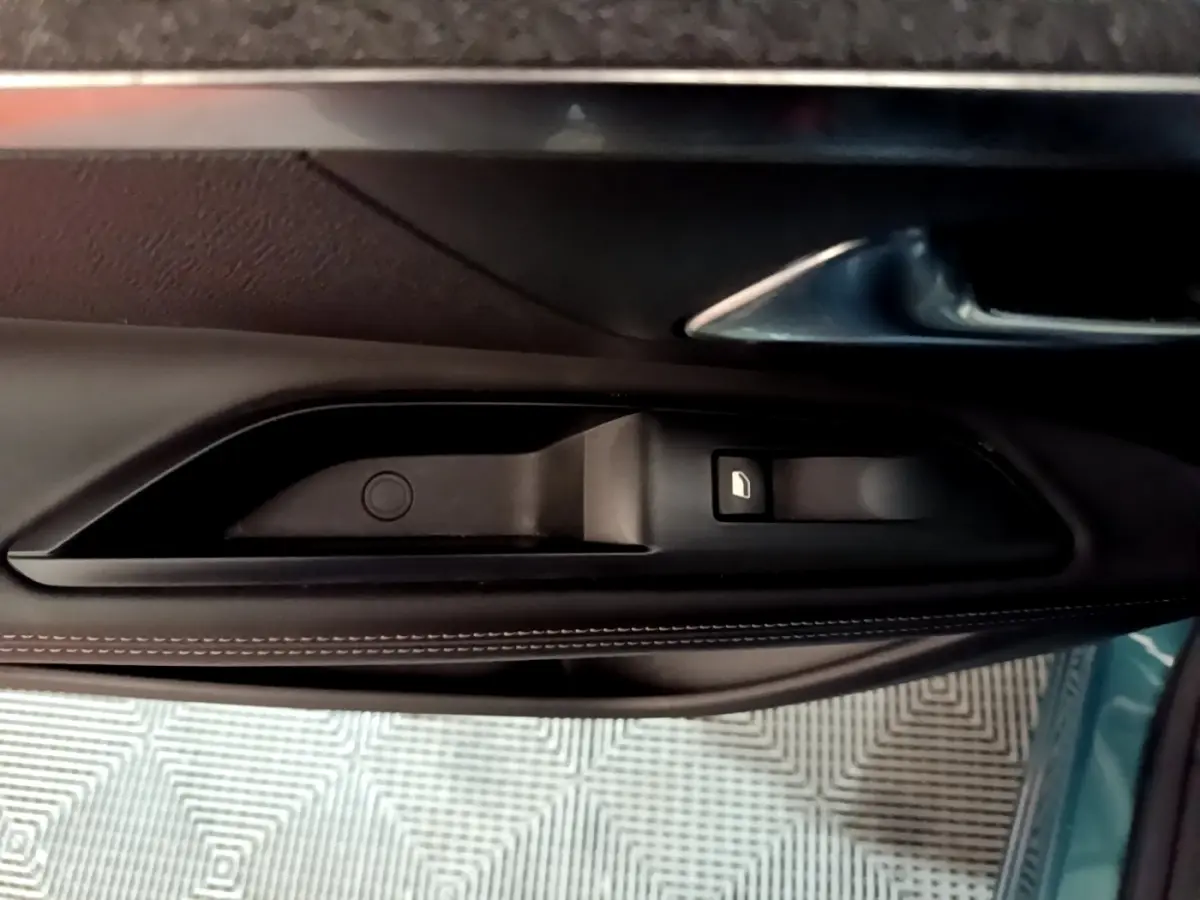 Poignée intérieure côté gauche de la porte d’un Peugeot 5008 bleu, avec bouton de verrouillage visible.