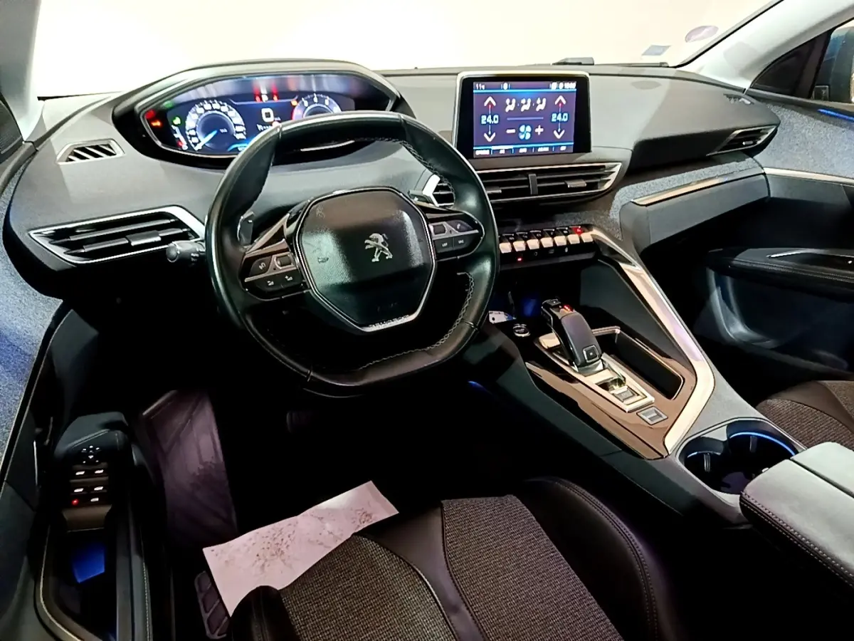 Intérieur Peugeot 5008 bleu 2018 vu côté conducteur, tableau de bord moderne avec écran tactile et volant cuir.