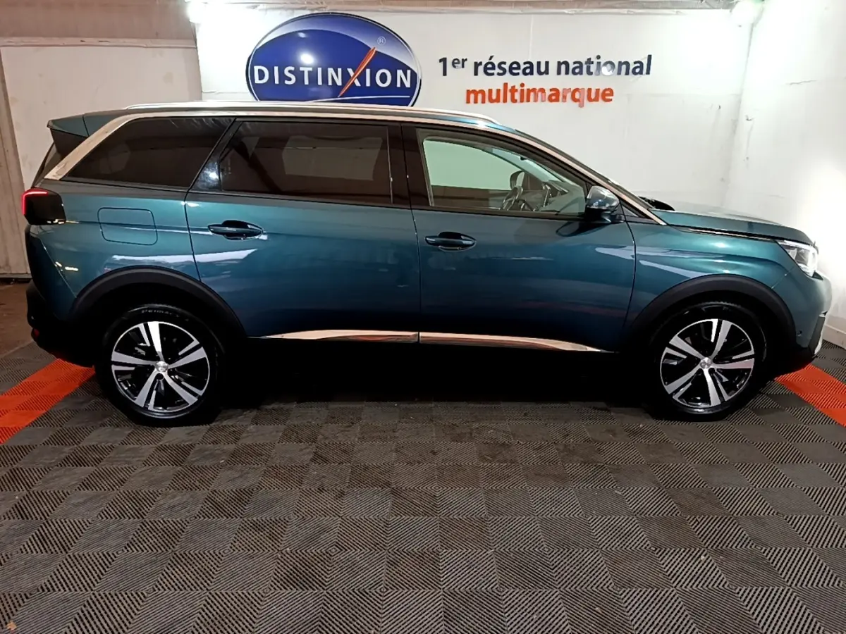 Profil côté droit du Peugeot 5008 bleu 2018 avec jantes alliage et vitres teintées dans un showroom intérieur.