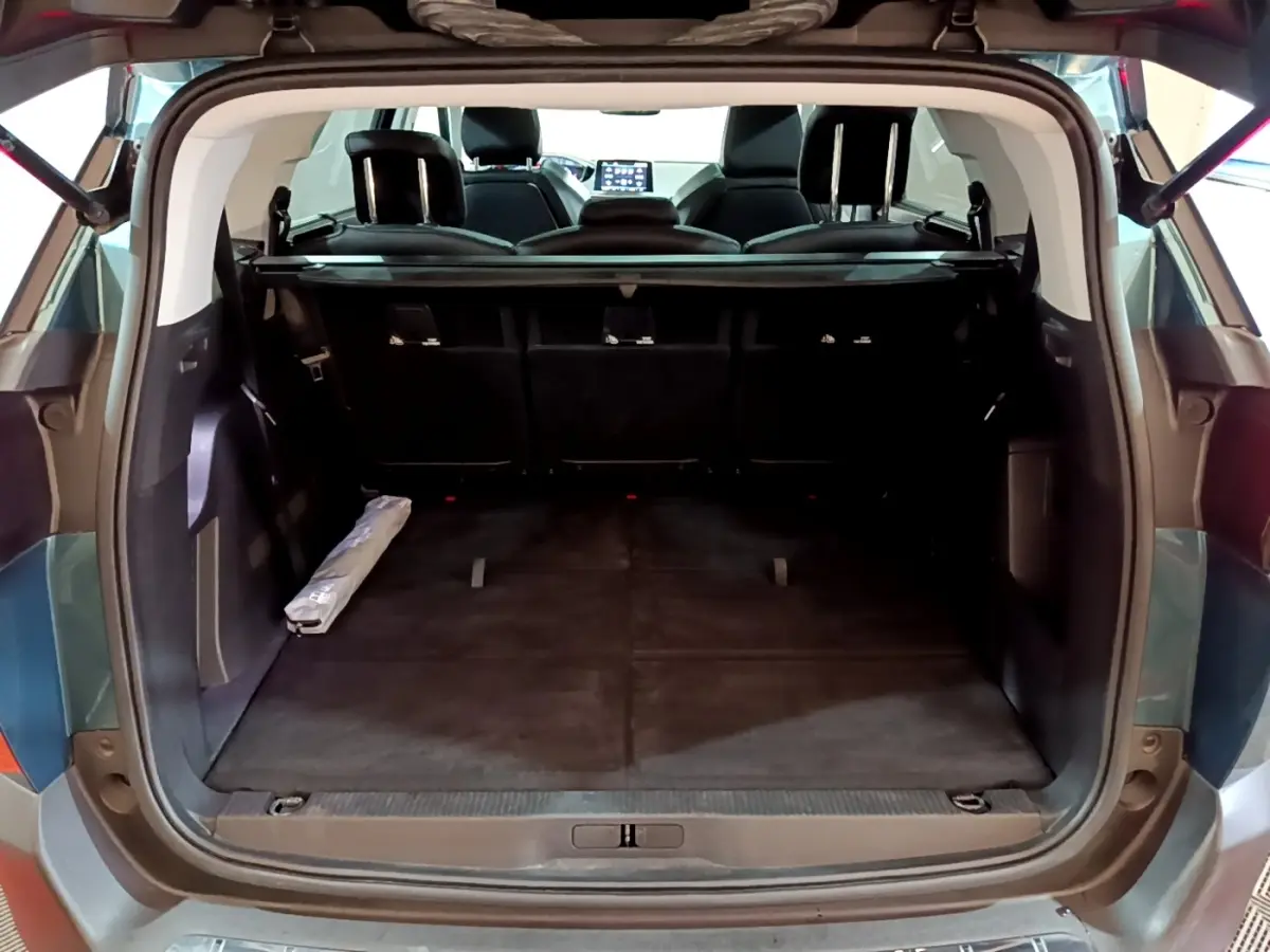 Coffre ouvert vu de l'arrière d'un Peugeot 5008 bleu 2018, montrant l'espace de chargement et sièges rabattus.