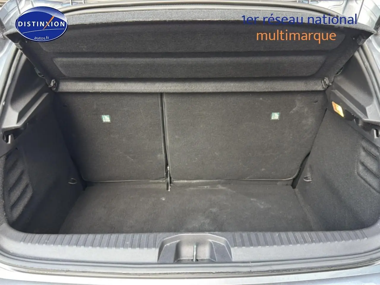 Coffre ouvert de la Renault Clio V gris, montrant l'espace de rangement avec banquette arrière rabattable.