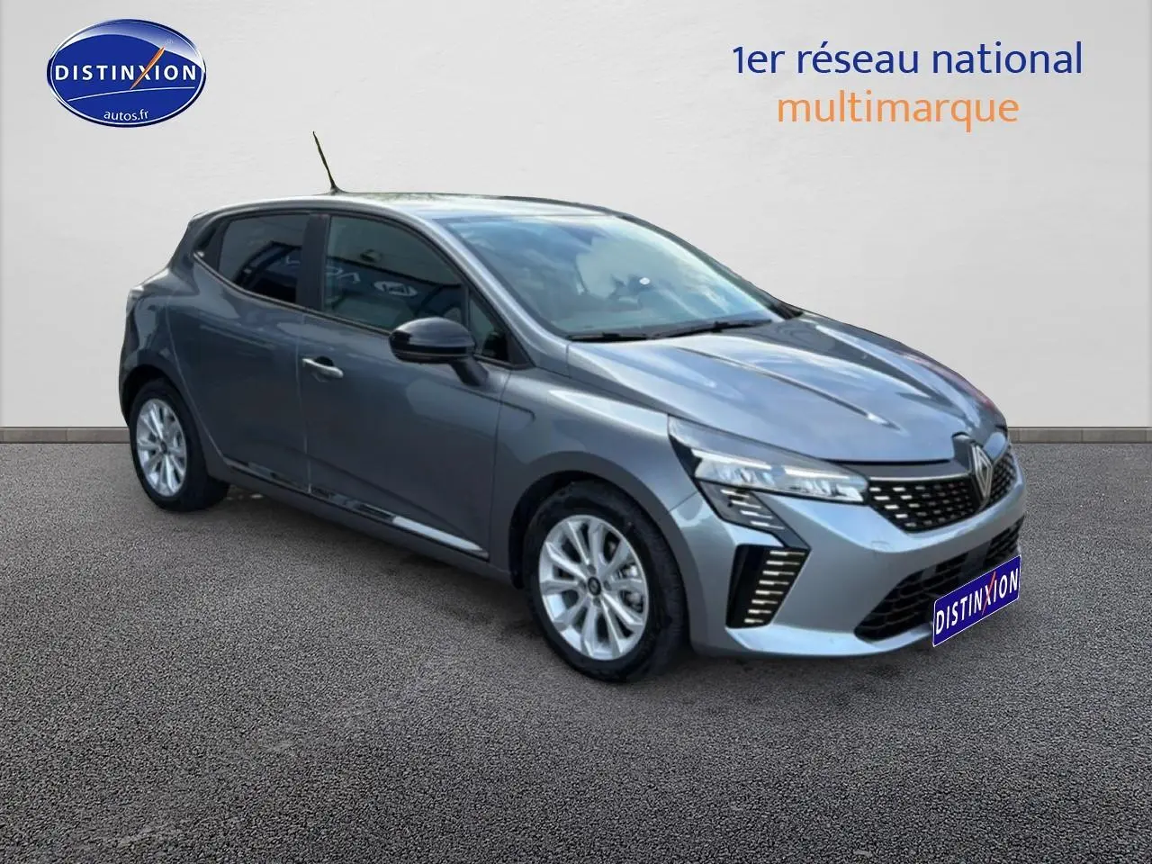 Renault Clio V gris en 3/4 avant droit, avec phares LED et jantes alliage visibles sur fond neutre.