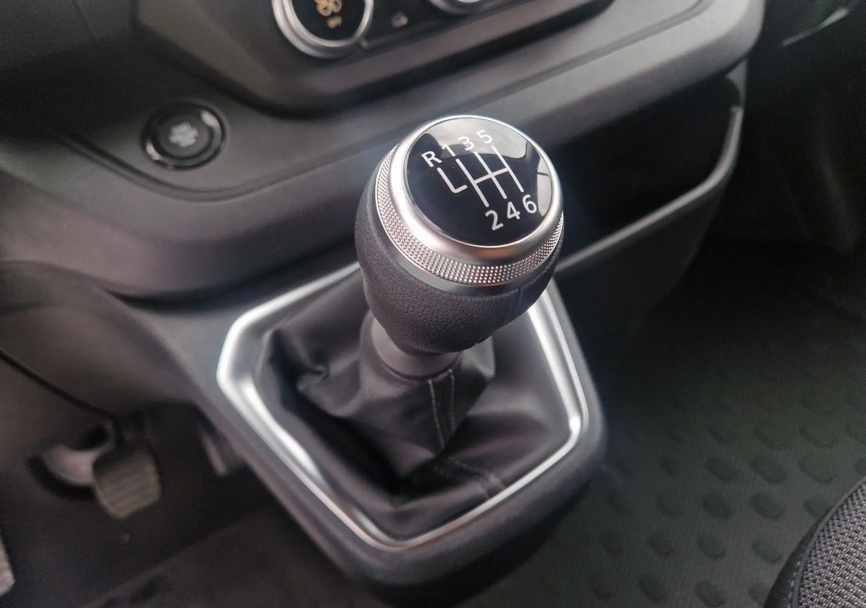 Gros plan sur le levier de vitesses manuel du Renault Trafic Fourgon 2025, entouré d’une console noire.