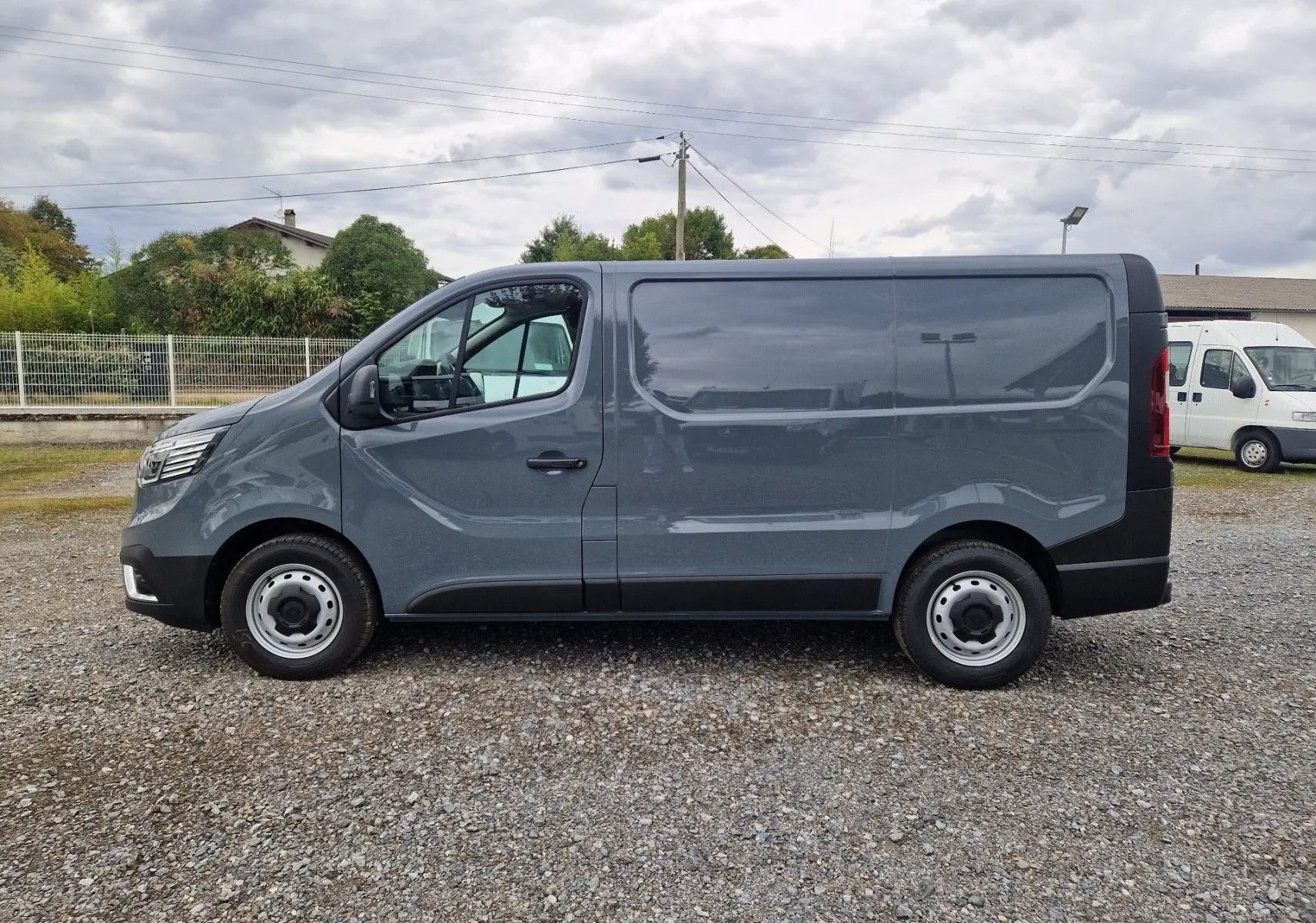 Vue latérale droite d'un Renault Trafic Fourgon gris urbain 2025, avec carrosserie lisse et roues acier.