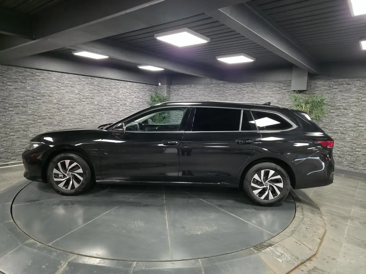 Vue latérale droite d'une Volkswagen Passat SW noire 2024 en hybride essence, avec jantes alliage et vitres teintées.