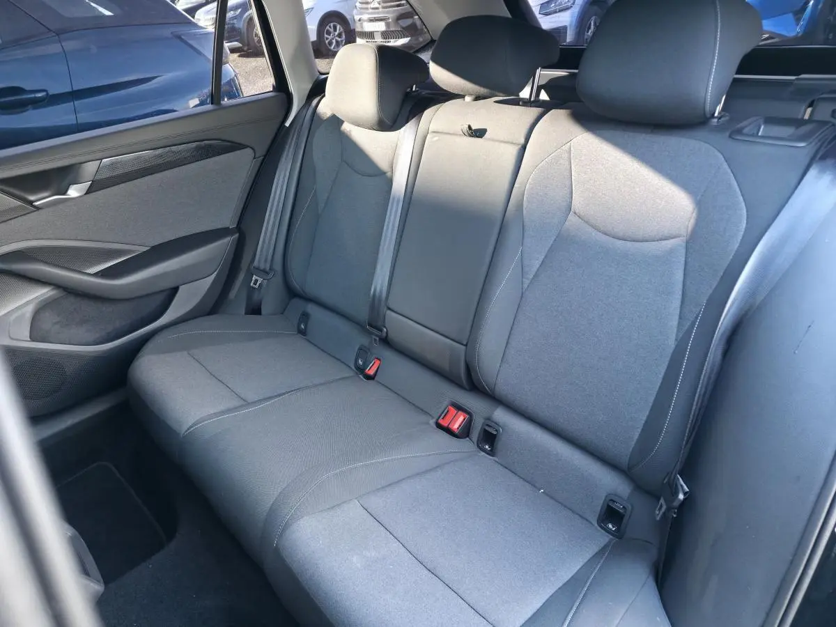 Vue intérieure côté droit des sièges arrière gris tissu de la Volkswagen Passat SW 2024, avec ceintures et appuie-têtes.