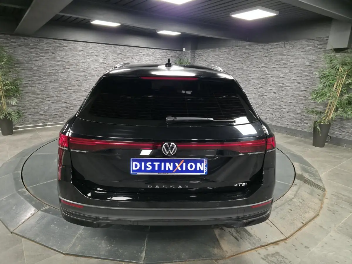 Vue arrière d'une Volkswagen Passat SW noire 2024 avec feux arrière LED continus et vitre arrière teintée.