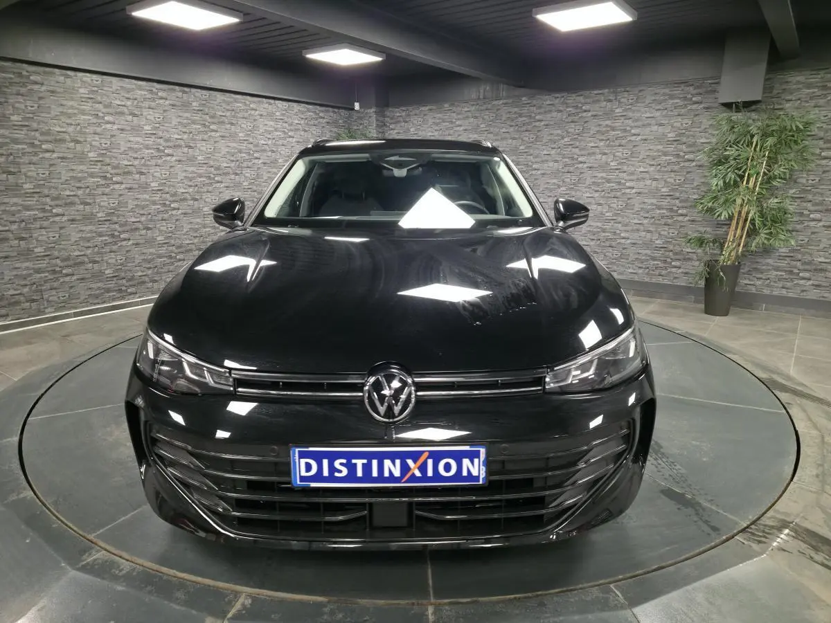 Volkswagen Passat SW noire vue de face dans un showroom avec éclairage et plaque Distinxion.