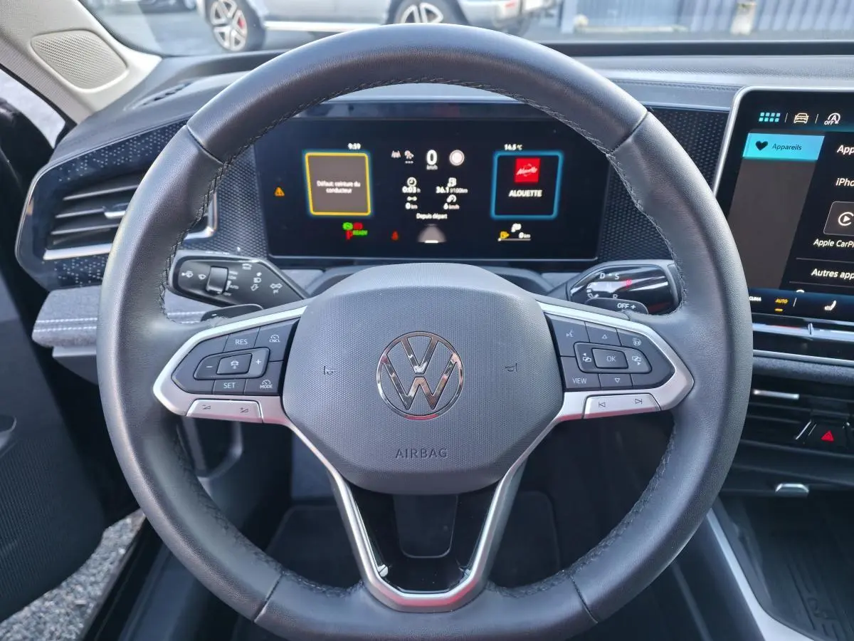 Vue rapprochée du volant cuir multifonction et du tableau de bord numérique de la Volkswagen Passat SW 2024.