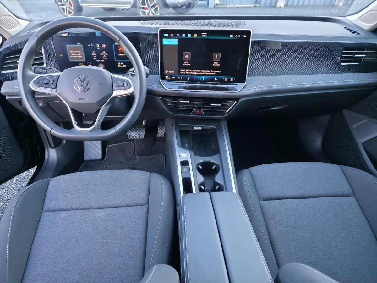 Vue intérieure avant de la Volkswagen Passat SW 2024, tableau de bord numérique et écran tactile 12,9 pouces, sièges gris.