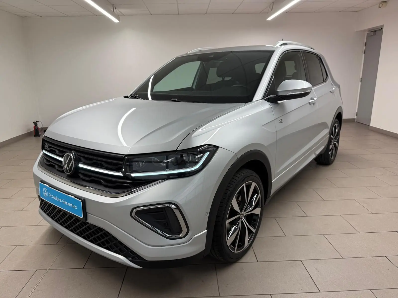 Volkswagen T-Cross 1.5 TSI R-Line en reflet d'argent, vue 3/4 avant droit avec jantes alliage noires et chromées.