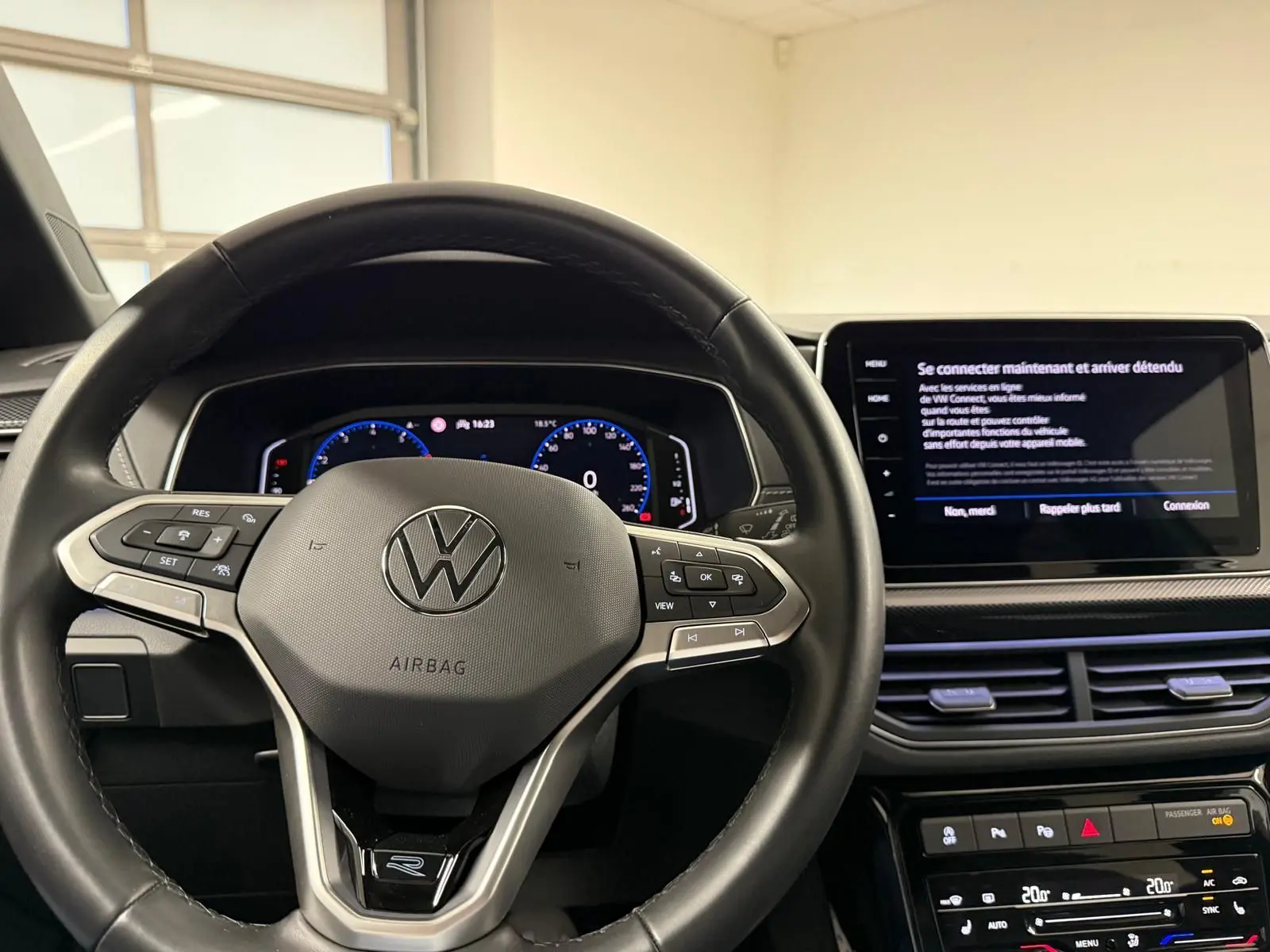 Vue intérieure centrée sur le volant cuir multifonction avec logo VW, tableau de bord digital et écran tactile du Volkswagen T-Cross.