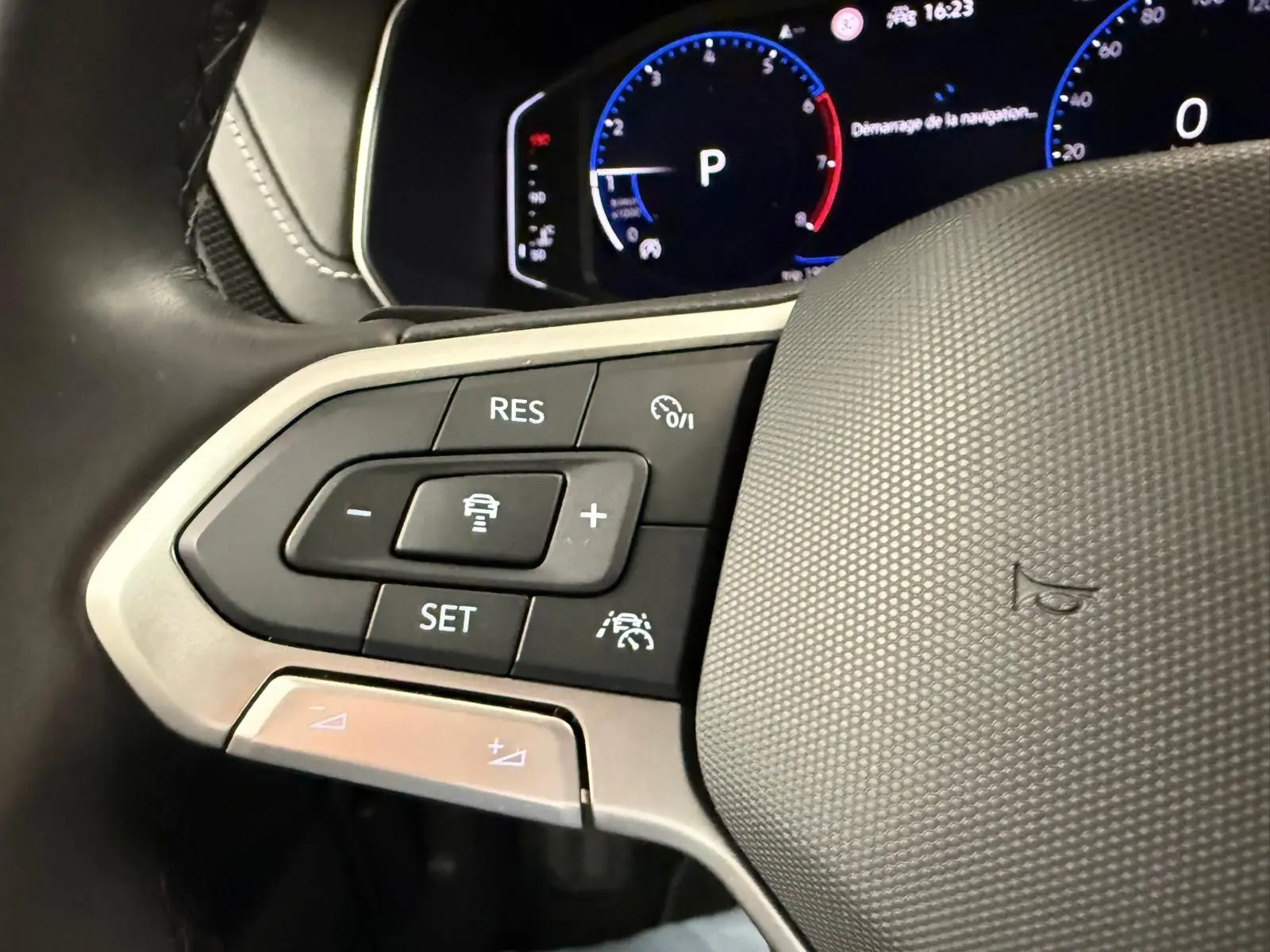 Gros plan sur les commandes du volant cuir du Volkswagen T-Cross 1.5 TSI 150 DSG7 R-Line, tableau de bord digital en arrière-plan.