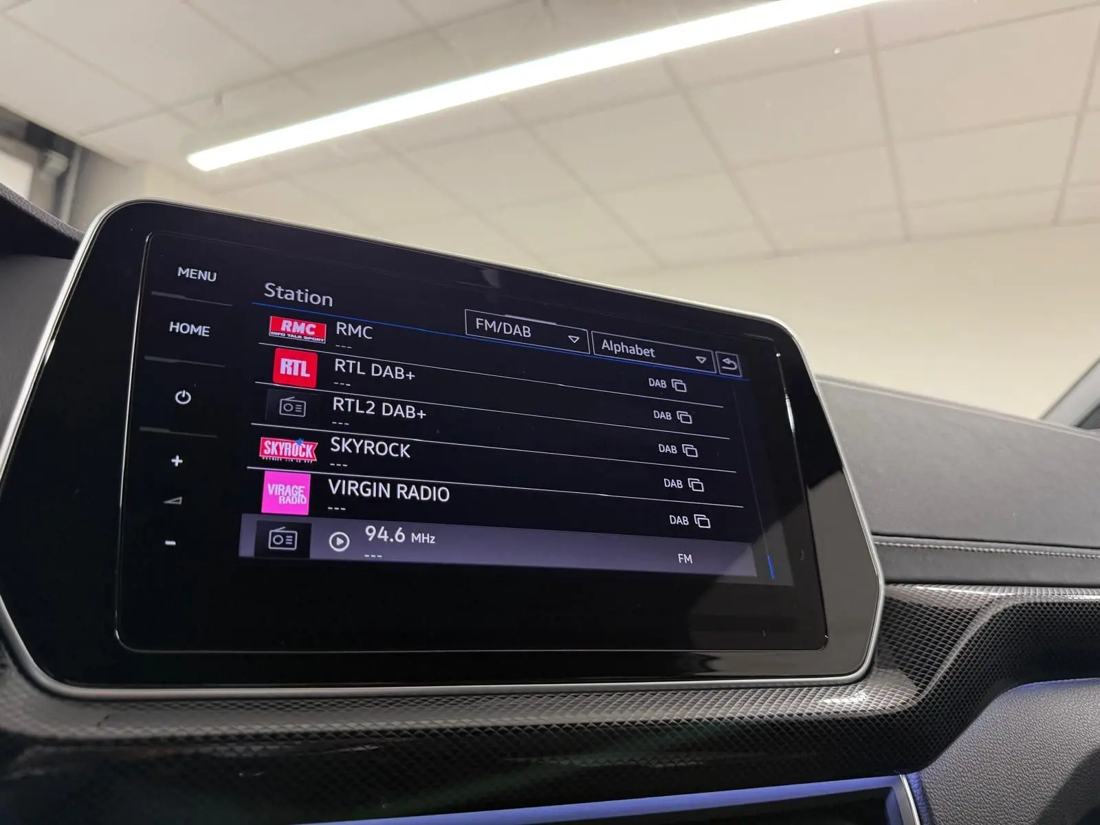 Écran tactile central du Volkswagen T-Cross 2024 affichant les stations radio FM/DAB en intérieur noir.