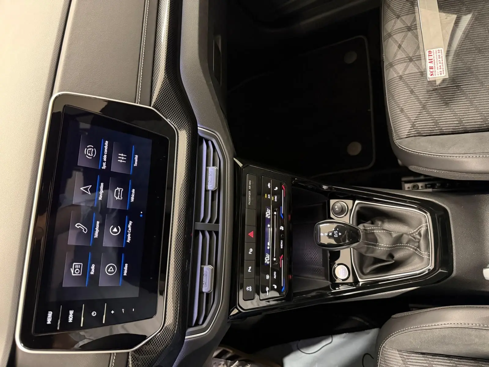 Vue intérieure centrée sur la console centrale et l'écran tactile du Volkswagen T-Cross 1.5 TSI R-Line, finition noire.