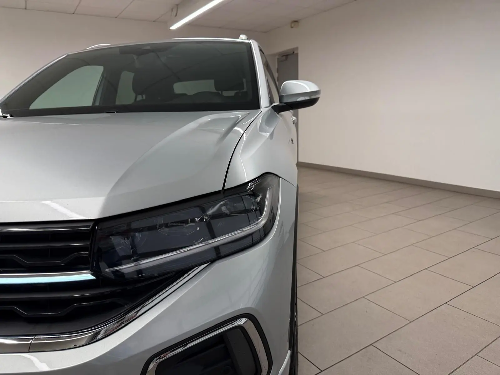 Gros plan sur l'avant droit du Volkswagen T-Cross 1.5 TSI R-Line en peinture métallisée Reflet d'Argent, avec phares Matrix LED.