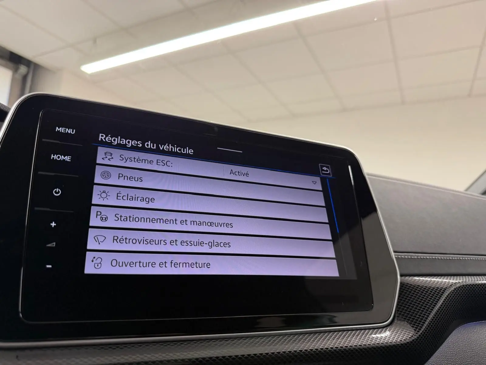 Écran tactile central du Volkswagen T-Cross 2024 affichant les réglages du véhicule, avec tableau de bord noir et inserts gris.