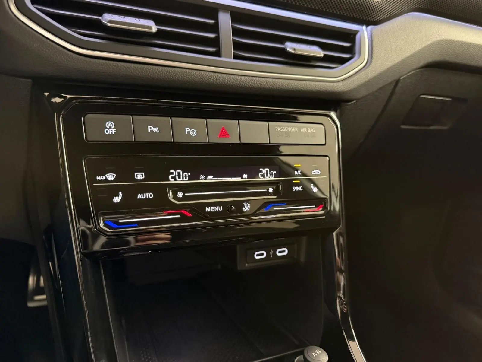 Détail de la console centrale noire brillante du Volkswagen T-Cross 1.5 TSI R-Line avec commandes climatisation tactile bi-zone.