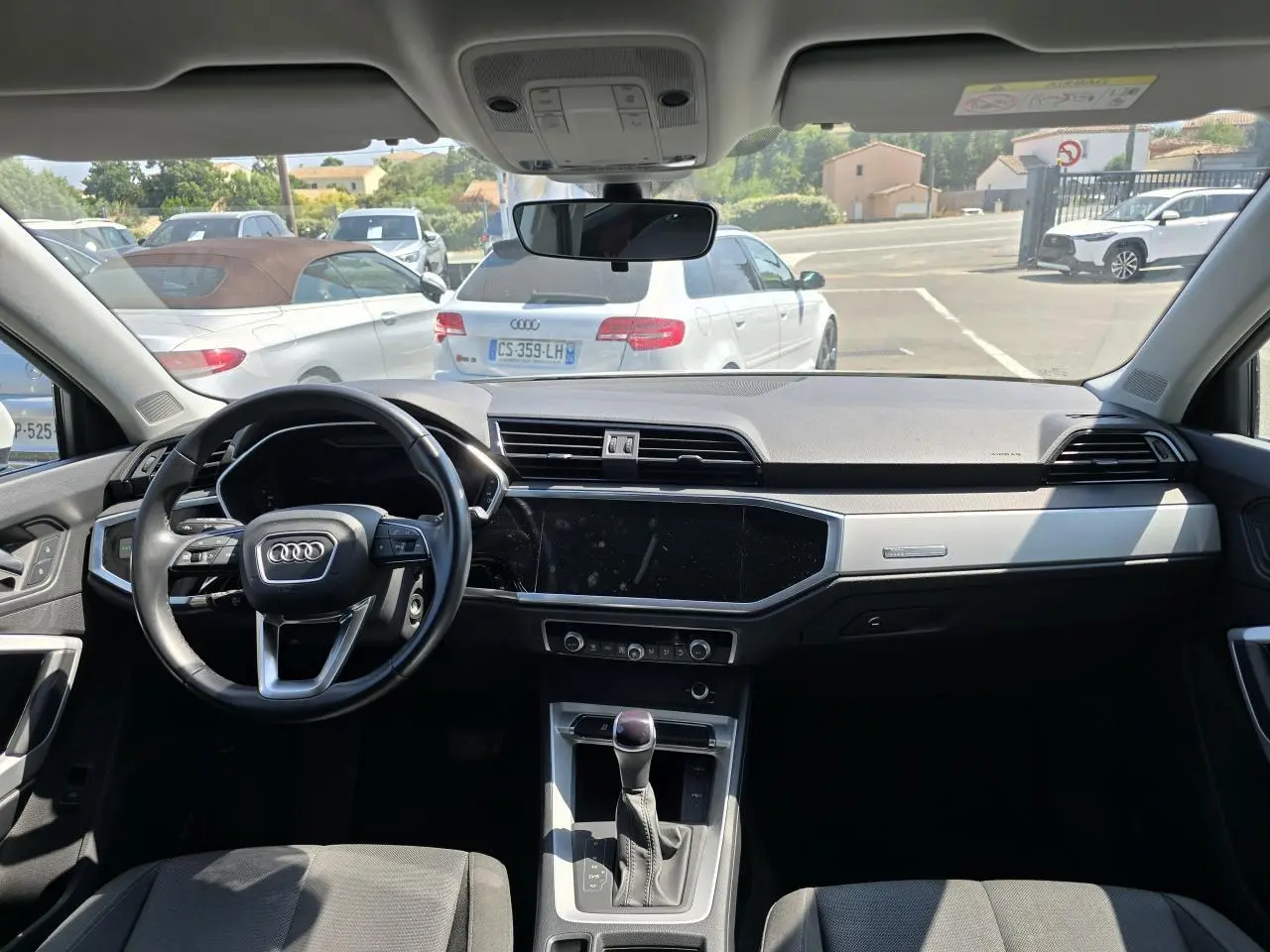 Vue intérieure avant de l'Audi Q3 2022, tableau de bord moderne avec volant cuir multifonctions et écran tactile central noir.