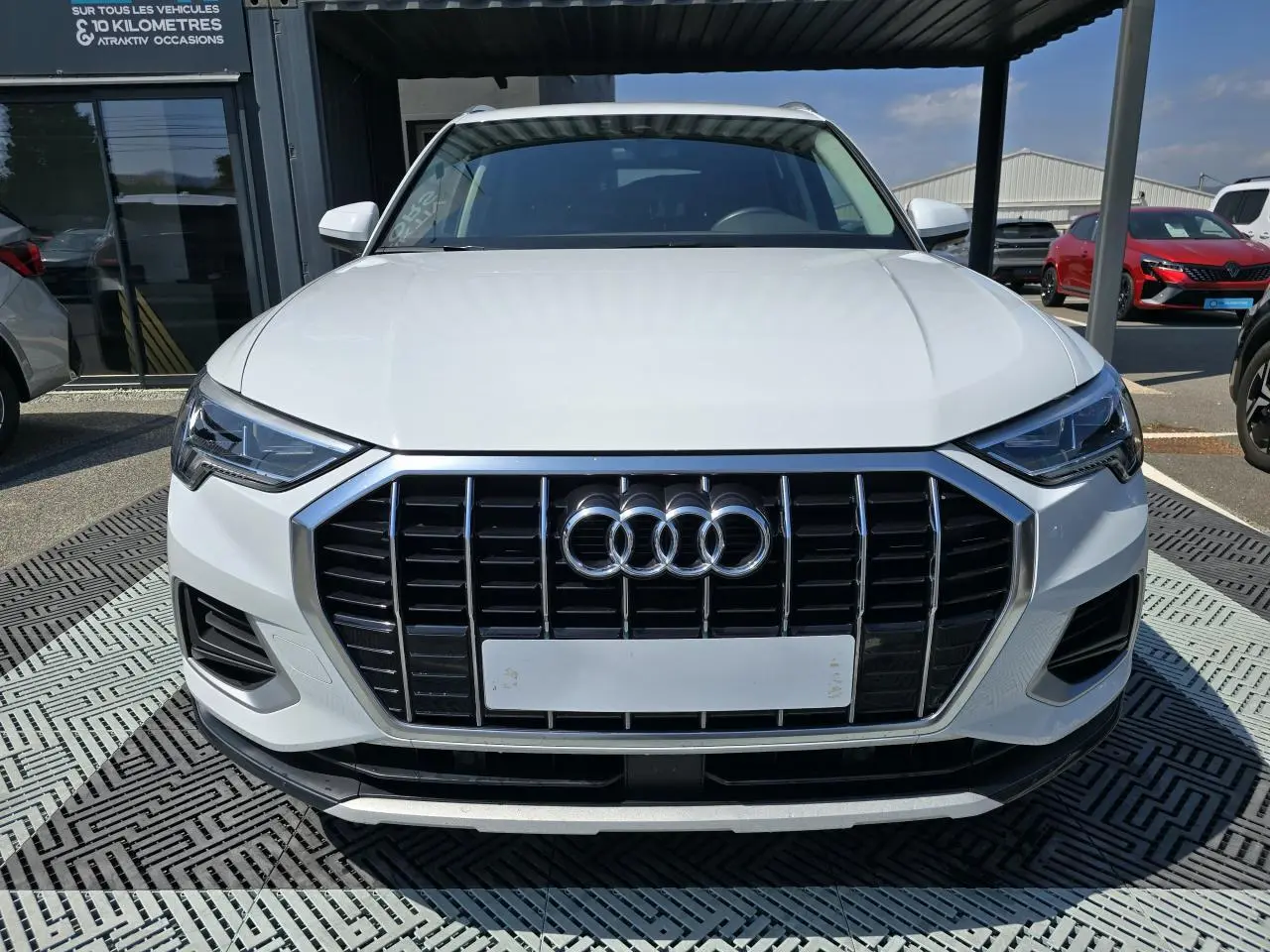Vue frontale d'un Audi Q3 blanc 2022 avec calandre noire et phares LED au design anguleux.