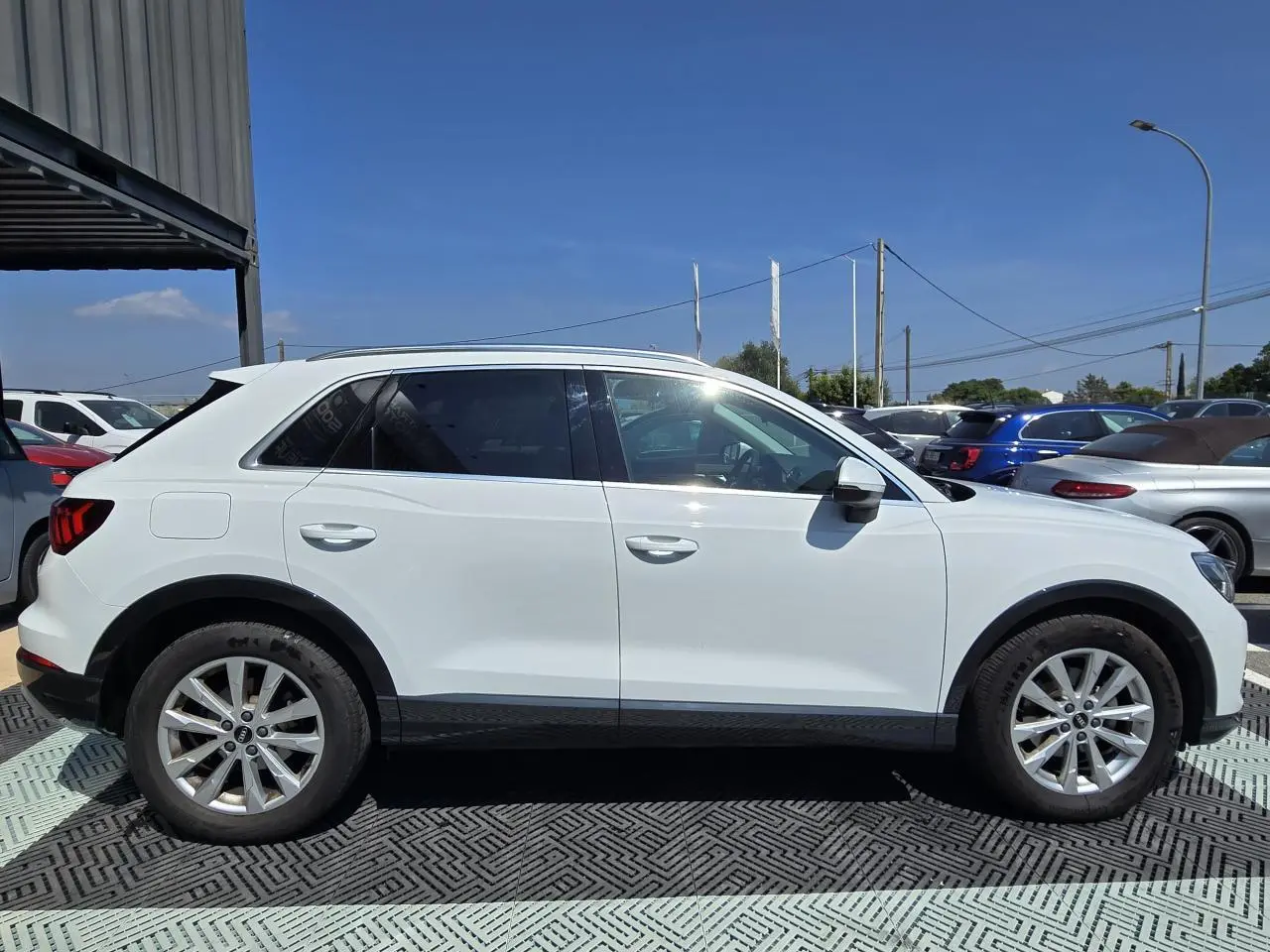 Audi Q3 blanc vue de profil côté gauche avec jantes aluminium 5 branches doubles et vitres arrière surteintées.
