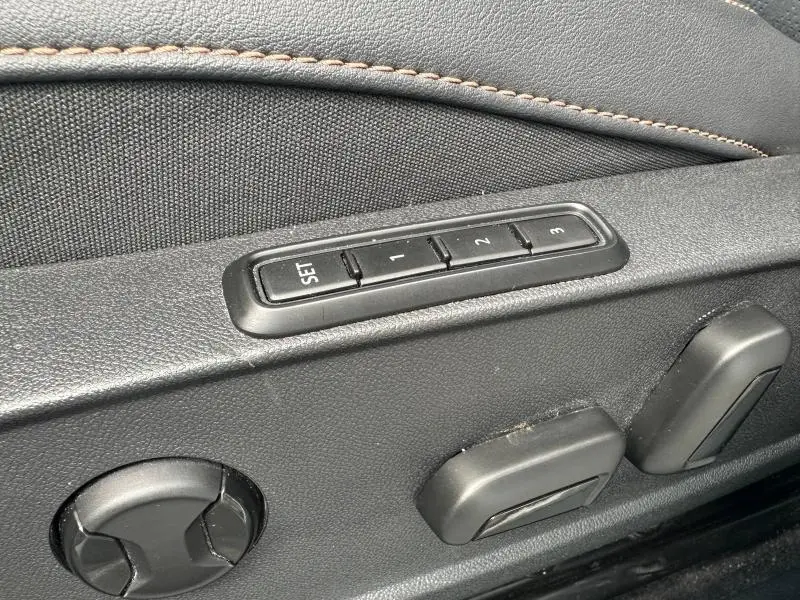 Détail des commandes de réglage électrique des sièges en textile noir avec surpiqûres marron dans une CUPRA Formentor blanc Nevada.