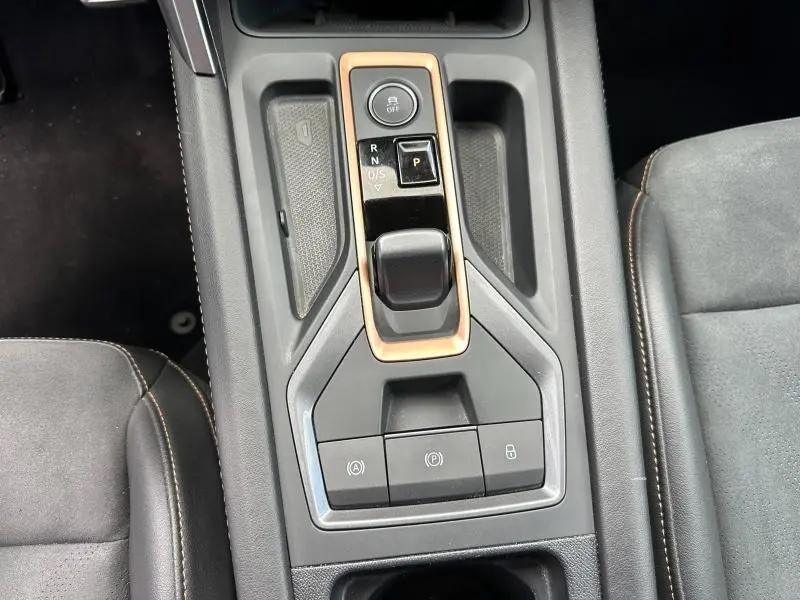 Vue plongeante sur la console centrale noire et grise du CUPRA Formentor 1.5 eTSI Hybrid avec levier de vitesse électronique et sièges en textile noir.