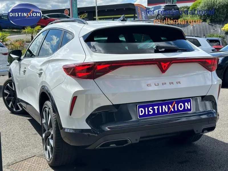 Vue 3/4 arrière droite d'une CUPRA Formentor blanc Nevada métallisé avec feux arrière LED reliés et jantes alu noires.