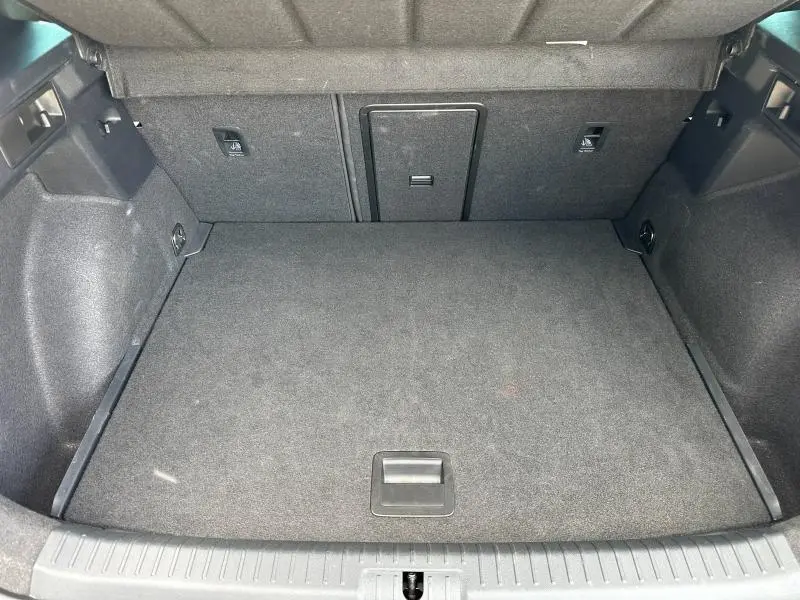 Coffre ouvert vu de face d'une CUPRA Formentor 1.5 eTSI Hybrid blanc Nevada, intérieur noir textile.