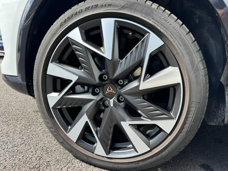 Gros plan sur la jante alu noire et argentée au design géométrique du CUPRA Formentor blanc Nevada 2025.
