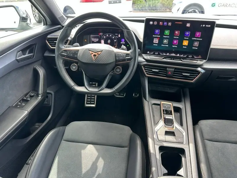 Vue intérieure avant du tableau de bord et volant cuir noir du CUPRA Formentor 1.5 eTSI Hybrid avec écran tactile central.
