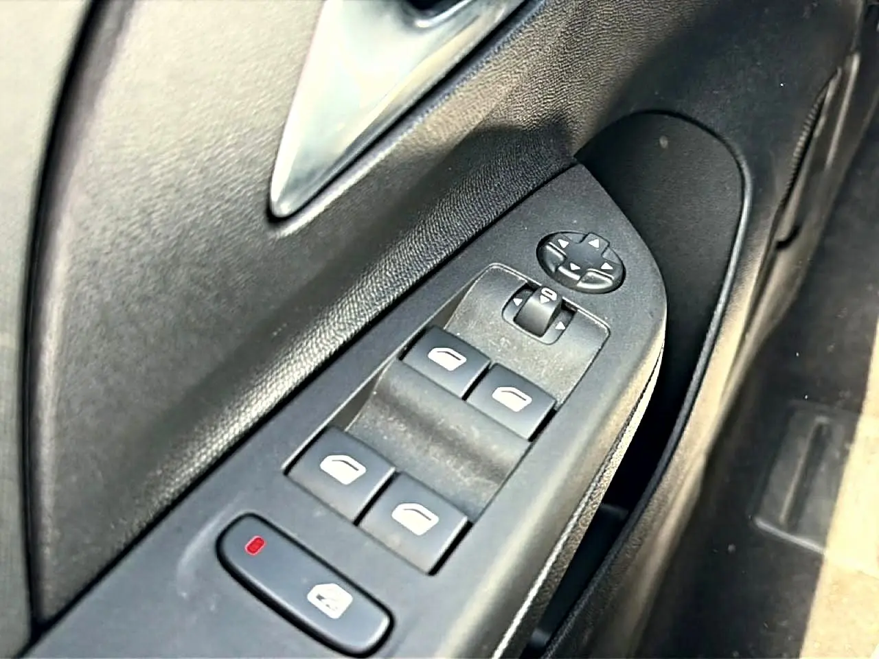 Gros plan sur les commandes de lève-vitres électriques côté gauche d'une Opel Corsa noire 2025.